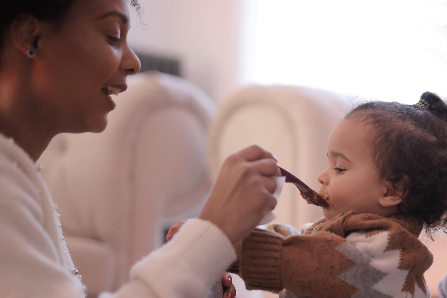 Mom feeding her toddler some yummy food