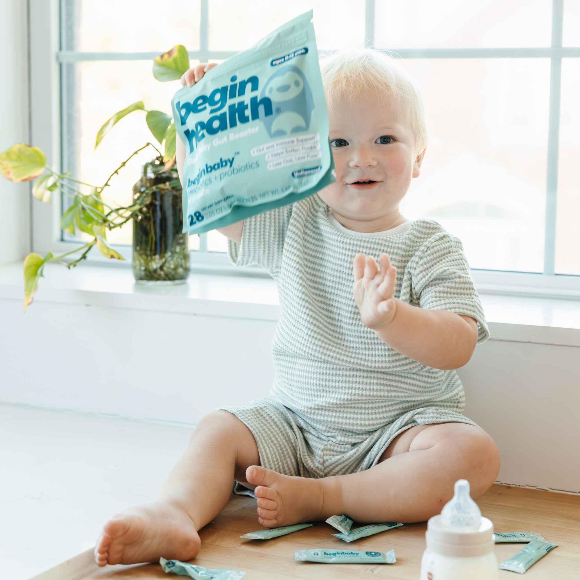 Child holding a container of prebiotics while lying on a couch.