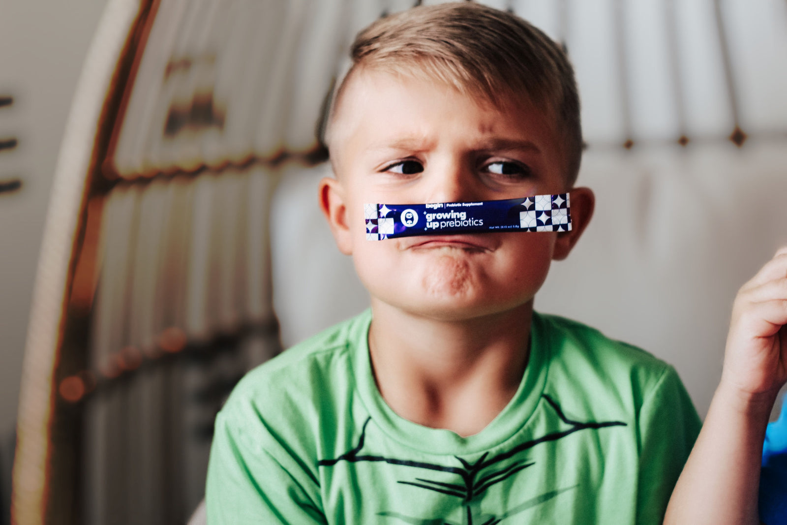 Little boy with a Begin Growing up Prebiotics packet on his nose